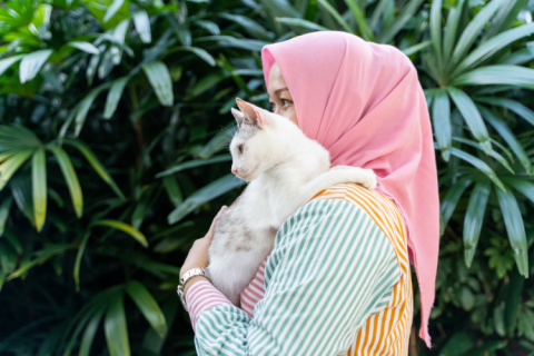 woman carrying a white cat
